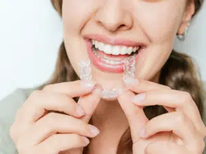 Man smiling and holding clear aligners illustrating drinking hot beverages with Invisalign considerations